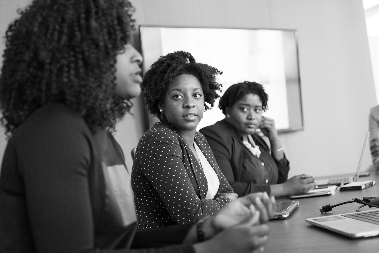 Group Of Women In Business Attire Sitting At A Table Having A Discussion.